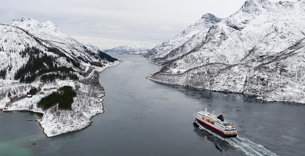Aerial view of fjord in cold winter weather with Hurtigruten ferry turist boat on the sea. Lofoten near Trollfjorden. Panoramatic photography in foggy weather.