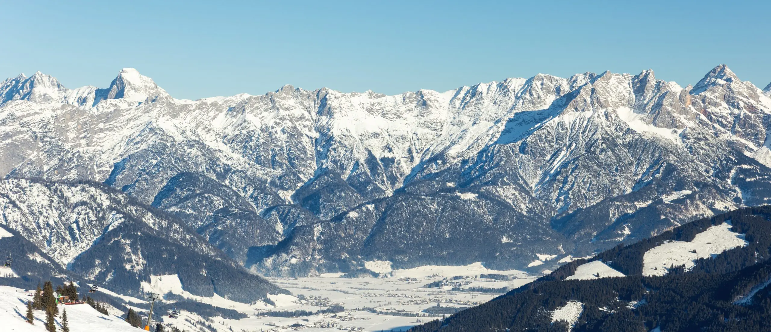 Scenic Saalbach-Hinterglemm-Leogang skicircus area snow-covered alpine mountains horizon sharp peaks illuminated sunlight. Valley forests ski slopes, chairlifts winter holiday activities white slopes