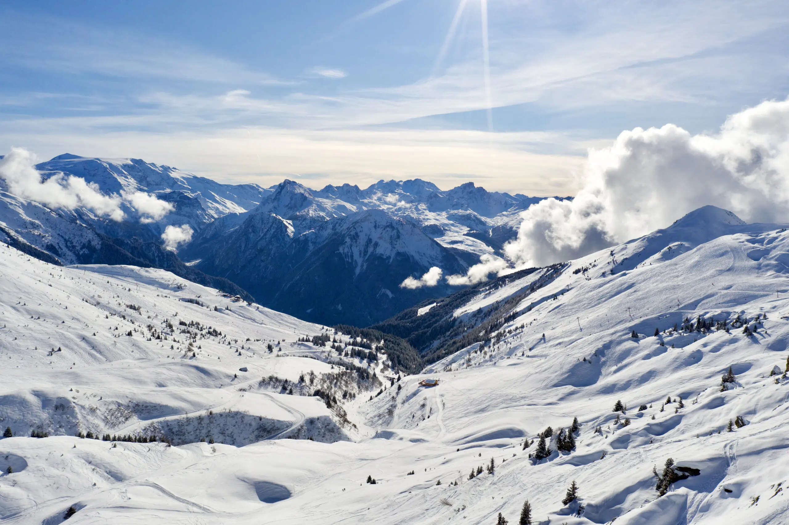 Arial shot of a mountain landscape in winter in the ski resort of La Plagne in the French Alps on a sunny day.