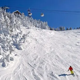 Skier on Mont Tremblant slopes with aerial gondolas on the background