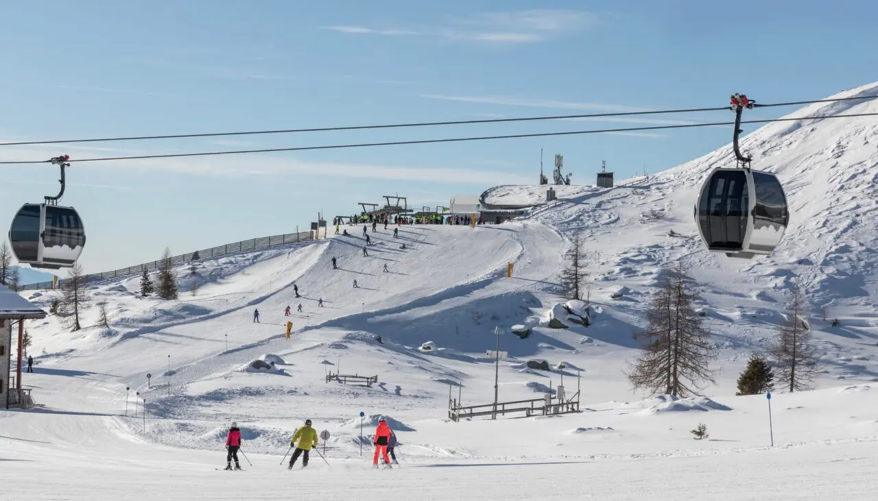 Ski slopes, skiers and cable cars on a sunny day in the Dolomites, Brenta area. Madonna di Campiglio, the top of the Pradalago cable car. Italy